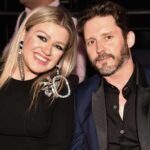 Kelly Clarkson smiles beside ex-husband Brandon Blackstock in a past public appearance, now mourning his passing while supporting their children.