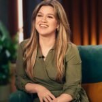 Kelly Clarkson smiles warmly while seated on set, marking her return to The Kelly Clarkson Show this fall after the loss of her ex-husband, Brandon Blackstock.